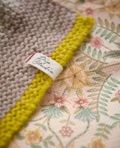 a close up of a knitted blanket with a tag on the end of it