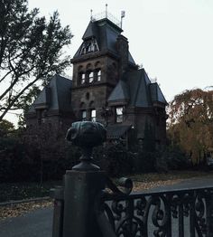 an old house with a wrought iron fence around it and trees in the foreground