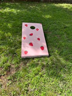 a pink cornhole board with strawberries on it