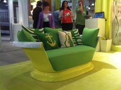 a green and yellow couch sitting on top of a floor next to a white table