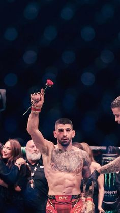 a man holding a rose in his right hand while standing next to another man on the other side