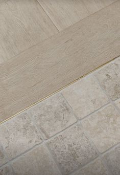 a white toilet sitting on top of a tiled floor next to a wooden door frame