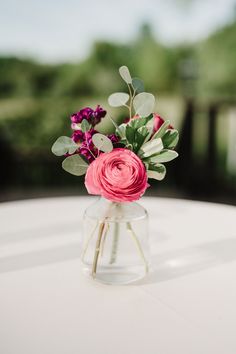 a vase filled with flowers sitting on top of a white table covered in greenery