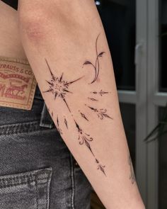 a woman's arm with a tattoo on it that has flowers and leaves drawn on it