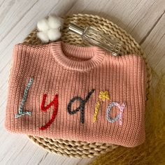 Welcome to our store! Step into the world of personalized baby sweaters! Each sweater is meticulously hand embroidered with your child's name in cursive on the chest or back. We offer your choice of chunky or extra chunky yarns to make each sweater unique. Each one-of-a-kind heirloom is customized and hand-embroidered on a high-quality, super soft, 100% cotton, oversized sweater (truly handmade by you  Every stitch is a labor of love. Our personalized sweaters make extraordinary gifts, perfect for baby welcome parties, delightful holiday surprises, joyous birthday celebrations, heartwarming group photos, precious milestone moments, or a unique way to say "Congratulations!" ! Impress the new mom or mom-to-be. Customized Details: Please be sure to provide all necessary personalization detail Pink Winter Sweater With Embroidered Logo, Personalized Cotton Sweater For Winter, Personalized Pink Crew Neck Sweater, Personalized Pink Long Sleeve Sweater, Cute Pink Sweater With Custom Embroidery, Personalized Pink Sweater For Winter, Handmade Cotton Crew Neck Sweater, Pink Cotton Sweater With Custom Embroidery, Name In Cursive