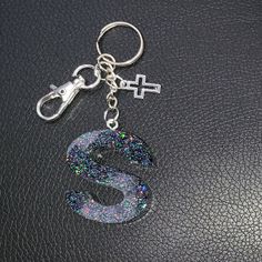 a keychain with the letter s on it is sitting on a black surface