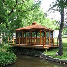 a wooden gazebo sitting next to a small pond in the middle of a park