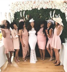 a group of women standing next to each other in front of a flower covered wall