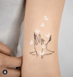 two hands touching each other with white butterflies flying around them on the left side of the arm