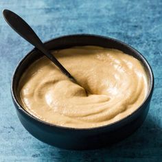 a black bowl filled with peanut butter on top of a blue tablecloth next to a spoon