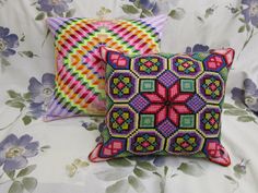 two decorative pillows on a bed with flowers