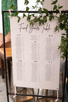 a seating chart for an event with greenery on the back and white paper underneath it