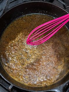 a frying pan filled with brown liquid and whisk on top of it