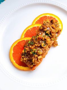 two pieces of fish on a plate with orange slices