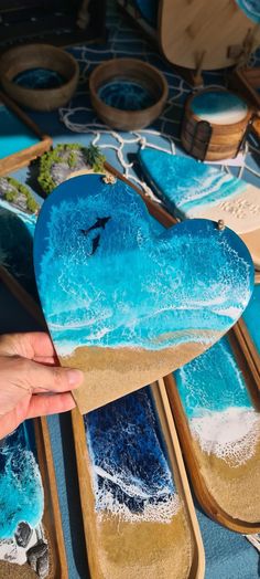 a person is holding up a heart shaped box that has been painted with blue and white paint