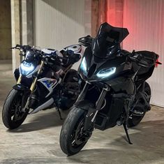 two motorcycles parked next to each other in a parking garage with red lights on them