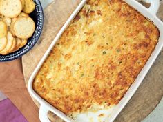 a casserole dish with some crackers next to it on a cutting board