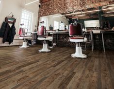 the interior of a barbershop with several chairs and stools in front of brick wall