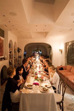 a group of people sitting at a long table with plates and glasses in front of them