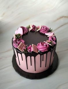 a chocolate cake decorated with pink roses and chocolate bars