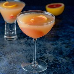 two glasses filled with drinks sitting next to each other on top of a black table