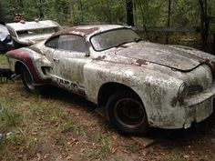 an old rusty car sitting in the woods