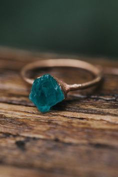 a close up of a ring with a green stone in it on a wooden surface