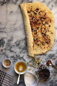 an uncooked pizza sitting on top of a table next to bowls and spoons