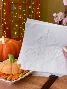 someone is holding up a napkin with the word monogrammed on it in front of some pumpkins