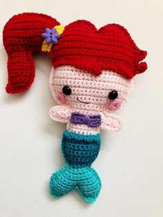 a crocheted little mermaid doll hanging on a wall