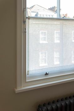 a window with white blinds in front of a radiator and wall mounted heater