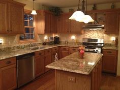 a large kitchen with wooden cabinets and granite counter tops, along with stainless steel appliances