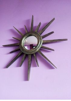 a sun shaped mirror mounted to the side of a wall next to a purple wall