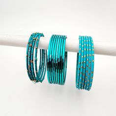 The Eliza Banglez Chest unveils a serene selection of bangles, a cascade of blues that range from sky blue to tones of teal. Over a hundred pieces form this set, accented with sprinkles of gold and subtle shimmers that reflect light when worn. Designed for both versatility and statement-making, these bangles allow for a personalized set that can gracefully style your look. Each piece in this collection is carefully crafted with a variety of textures and finishes, including glossy, matte, and emb Sprinkles, Sky Blue, Bangles, Range, Texture, Gold, Blue, Design