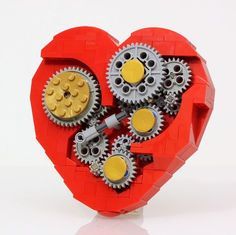 a red heart shaped object with gears attached to the side and yellow wheels on it