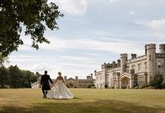 a bride and groom holding hands in front of a castle