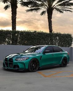 a green sports car parked in a parking lot next to two palm tree's