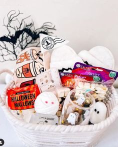 a white basket filled with lots of halloween treats and candies on top of a table