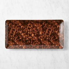 a marbled rectangular tray with brown speckles on the edges and bottom, sitting on a white surface