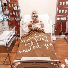 a woman laying in a hospital bed with a blanket that says god grant my heart needs you