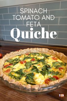 spinach, tomato and feta quiche in a glass pie dish on a wooden table