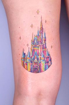 a colorful tattoo on the leg of a woman with a castle in front of it