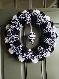 a black and white wreath hanging on the front door with a jack skellingy ornament