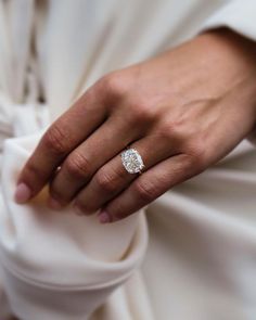 a woman's hand with a diamond ring on her left wrist, wearing a white dress