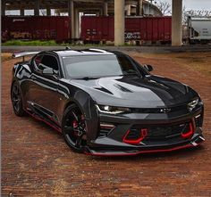 the chevrolet camaro zr1 is parked in front of a train track with red and black stripes