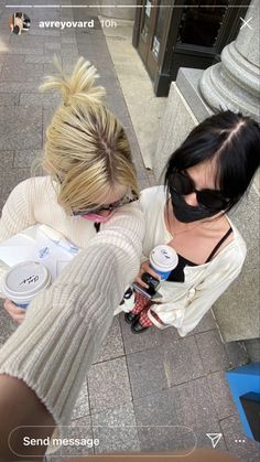 two women standing next to each other on a sidewalk