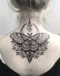 the back of a woman's neck with a moth tattoo on it