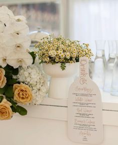 a table with flowers and wine glasses on it next to a sign that says welcome