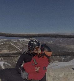 two people hugging each other on top of a mountain