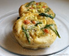 two small pastries sitting on top of a plate covered in cheese and veggies